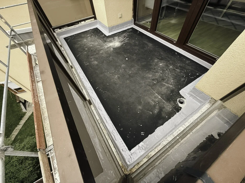 Balkonfläche mit dunkler Flüssigkunststoff-Beschichtung, umlaufende Anschlüsse an Türschwelle, Entwässerungskehlen und Profil