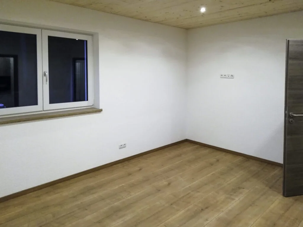 Leerer Raum in Mietwohnung: wei&szlig;e W&auml;nde, Holzoptik-Boden, Fenster, Deckenbeleuchtung